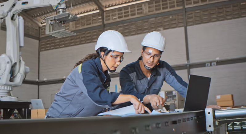 Industrial employees reviewing work data near equipment