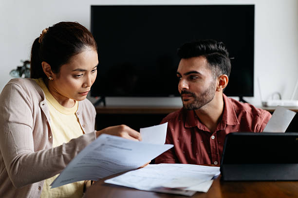 Two people looking at a laptop and papers