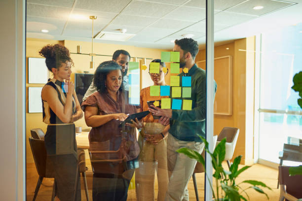 Group of people looking at a glass wall with sticky notes