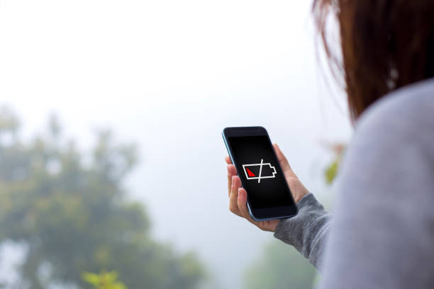 Person holding a smartphone showing low battery icon outdoors