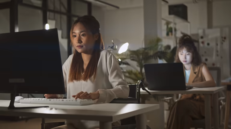 Two women working at computers in a dimly lit office