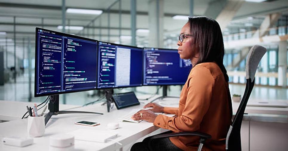 Employee working at multiple monitors, representing transparency and performance visibility