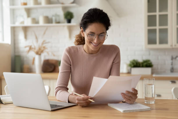Woman smiling looking at papers and laptop