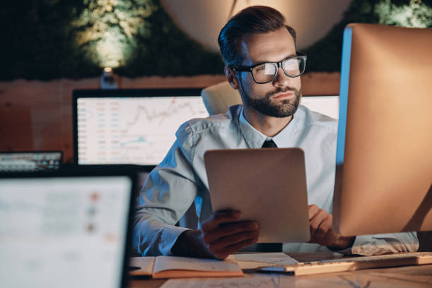 Man looking at computer screens in a dark office