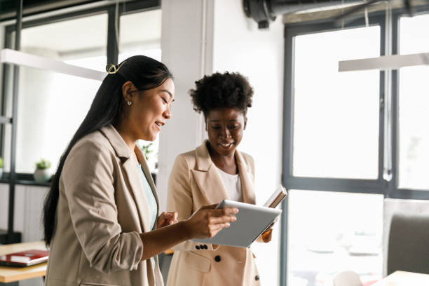 Two women standing in an office, one holding a tablet