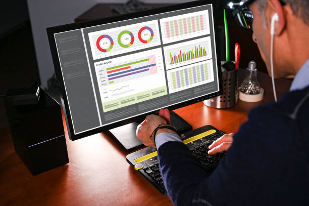 Person typing on a keyboard with charts on monitor