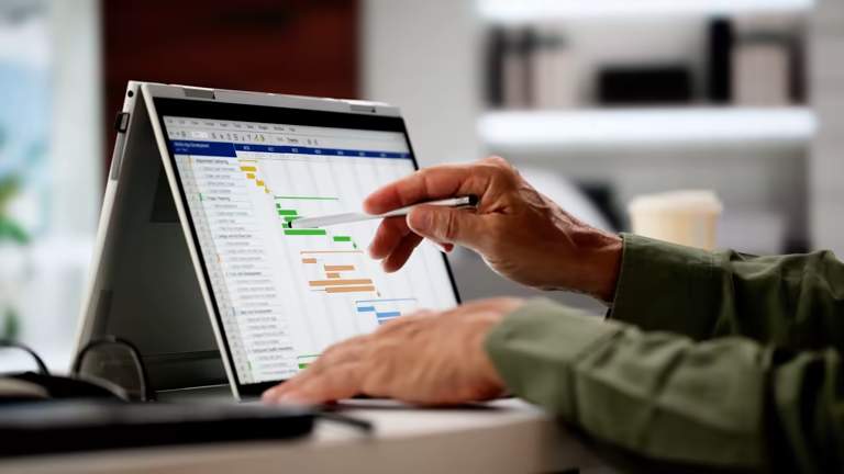 Hands pointing at a laptop screen showing a schedule or chart
