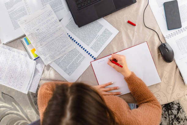 Person writing in a notebook with analytics and papers on the desk