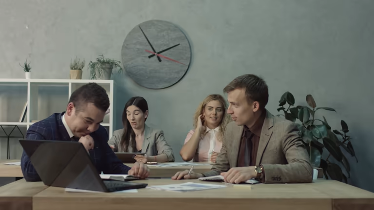 Employees checking laptop with a clock on the wall
