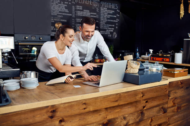 Two people looking at a laptop in a cafe setting