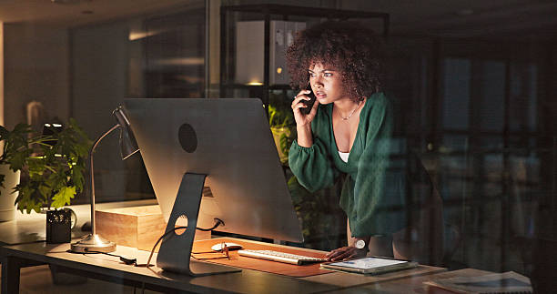 A woman on a phone looking at a computer screen