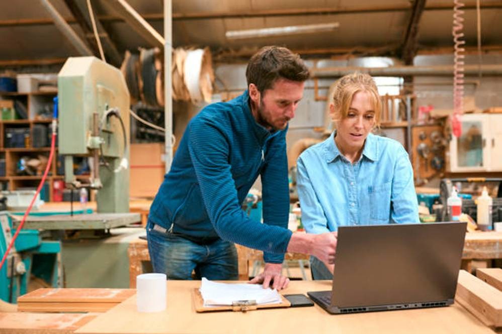 Small business employees reviewing payroll and time clock software on a laptop