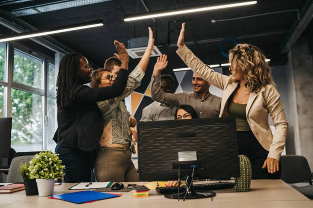 Team celebrating together in an office after reducing burnout and workload stress