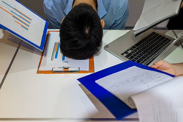 Employee resting head on desk representing absenteeism