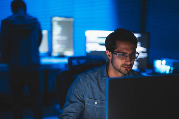Man looking at computer screens in a dark room