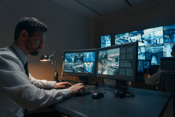 Man working at multiple monitors in a dark room