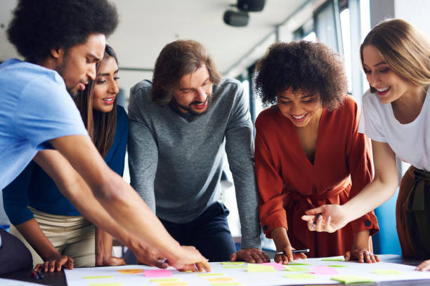 A diverse group of people looking at a table with sticky notes