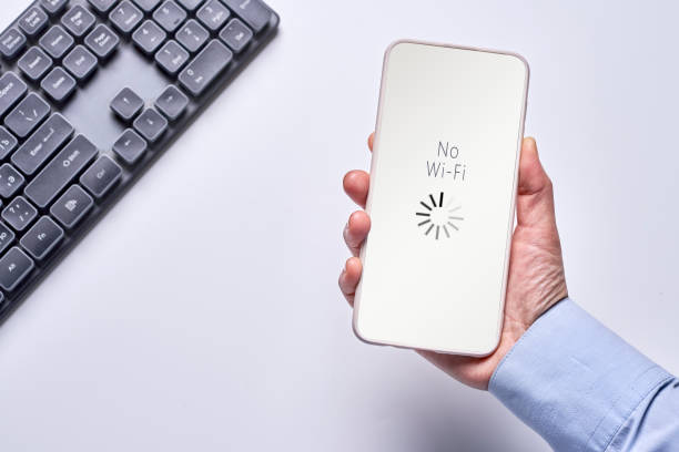 Hand holding a phone with No Wi-Fi symbol over a keyboard
