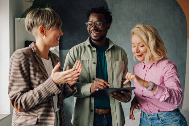 Three people smiling and looking at a tablet