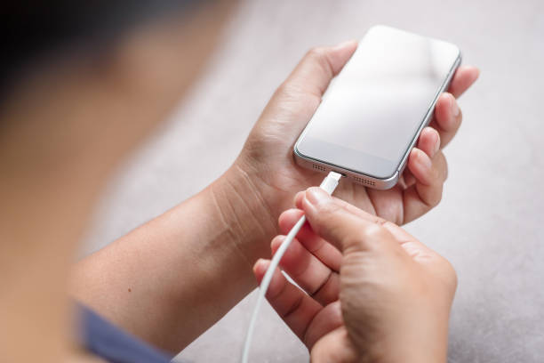 Person plugging a charging cable into a smartphone