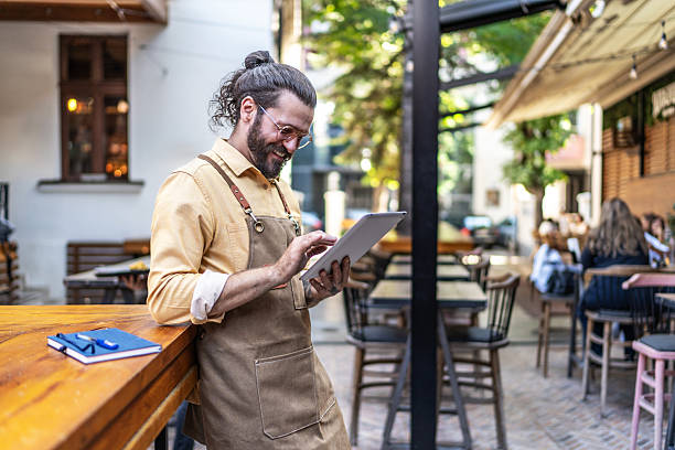 Man in apron using a tablet in a restaurant setting