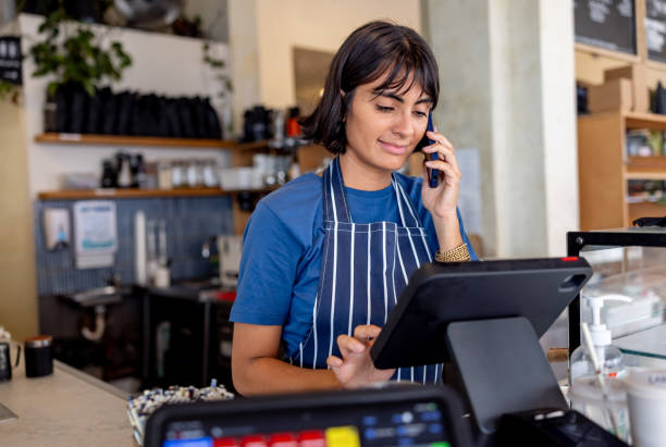 Woman at a POS terminal smiling and talking on the phone