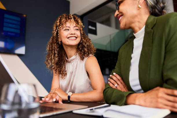 Two women looking at a laptop discussing field resource allocation