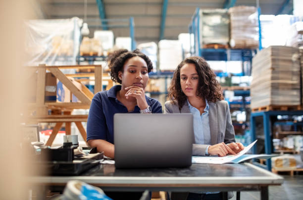 People looking at laptop in warehouse