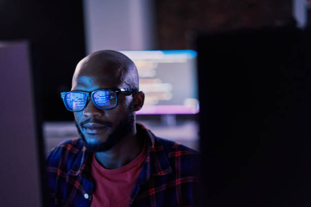 Man with glasses looking at a screen
