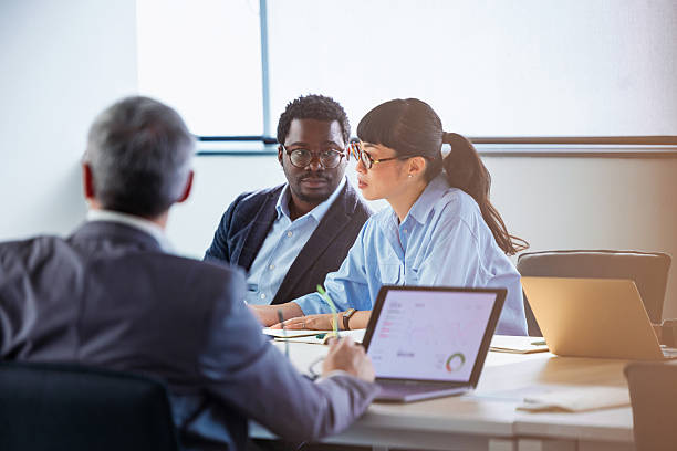 Three people in a meeting looking at a laptop