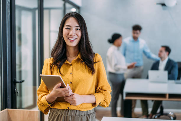 Woman smiling holding a tablet in an office