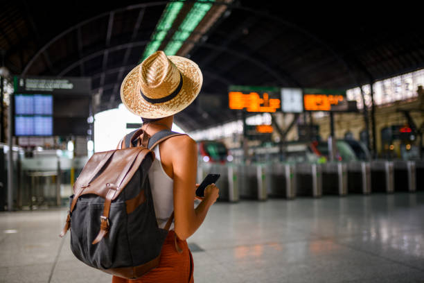 Person with a backpack looking at a train station departure board