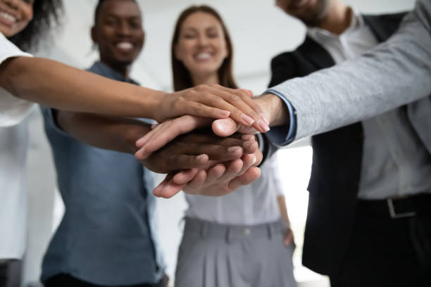Diverse team stacking hands together in unity