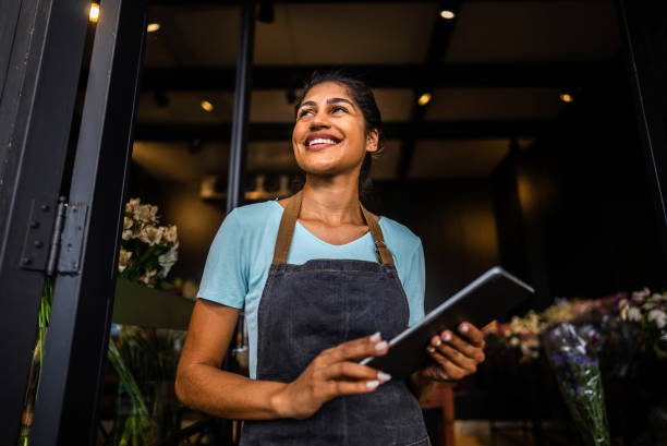 A smiling woman holding a tablet in a shop