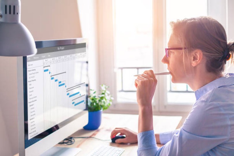 Employee reviewing project schedule and time tracking data on a computer