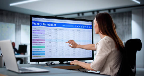 Person pointing at a weekly timesheet on a computer screen
