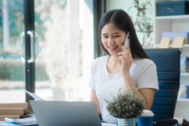 Woman smiling looking at a laptop in an office setting
