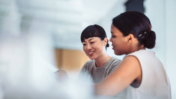 Two women looking at a laptop discussing work