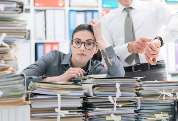 Stressed woman with paperwork and manager pointing at watch