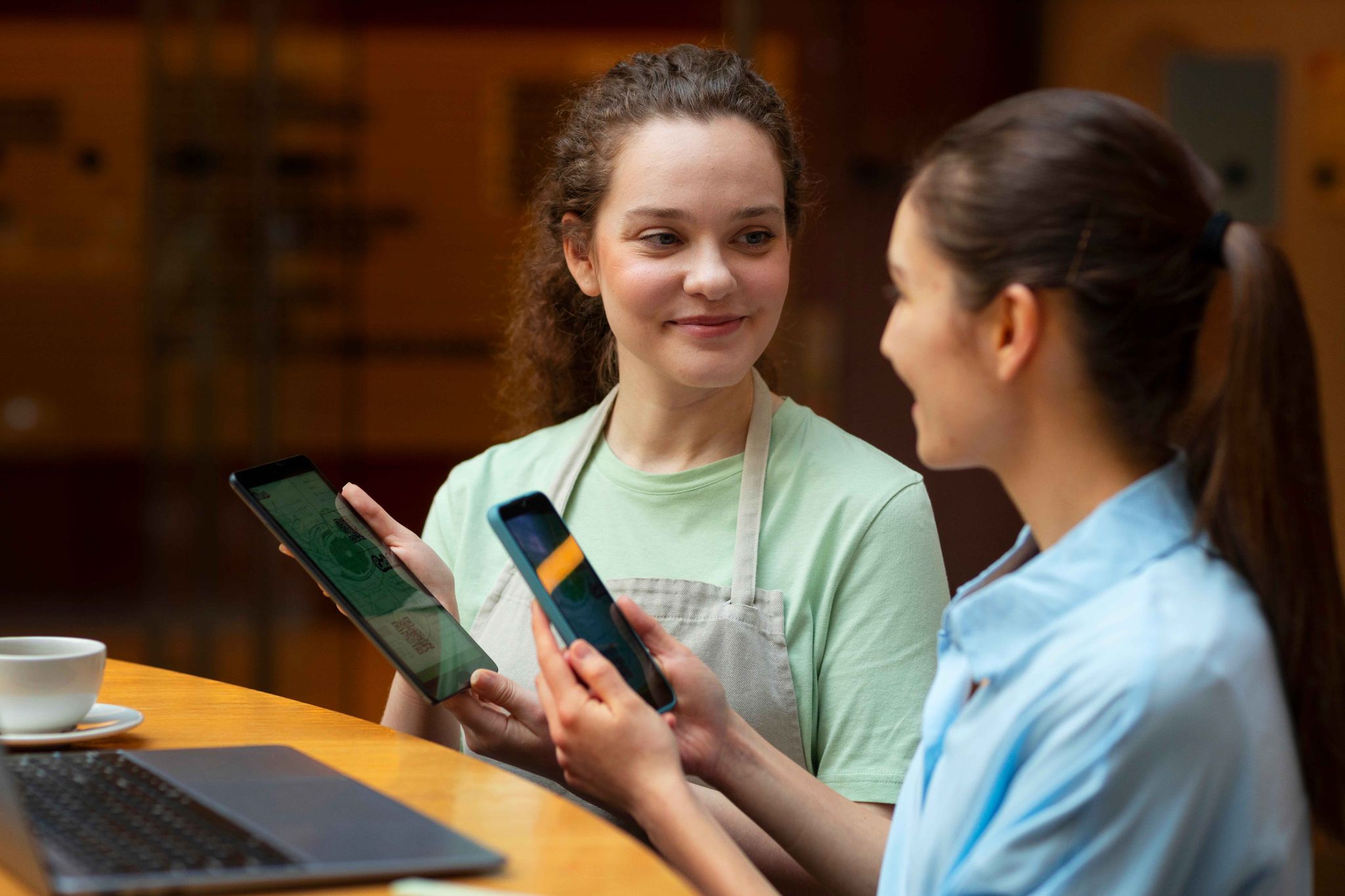 Two women looking at a tablet and phone