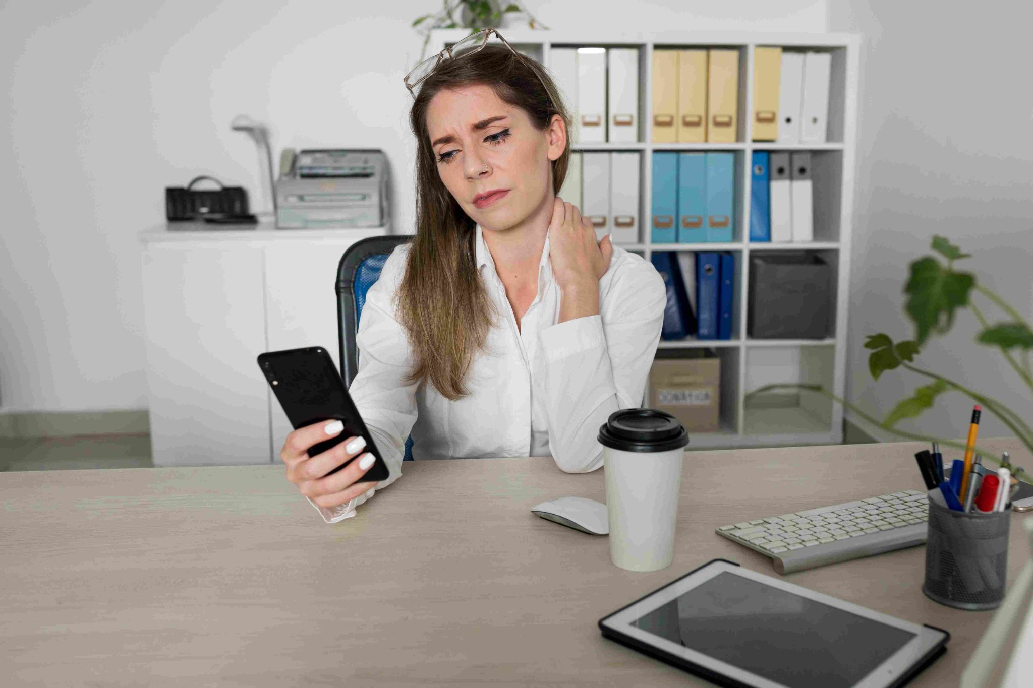 Stressed woman looking at her mobile phone at her desk
