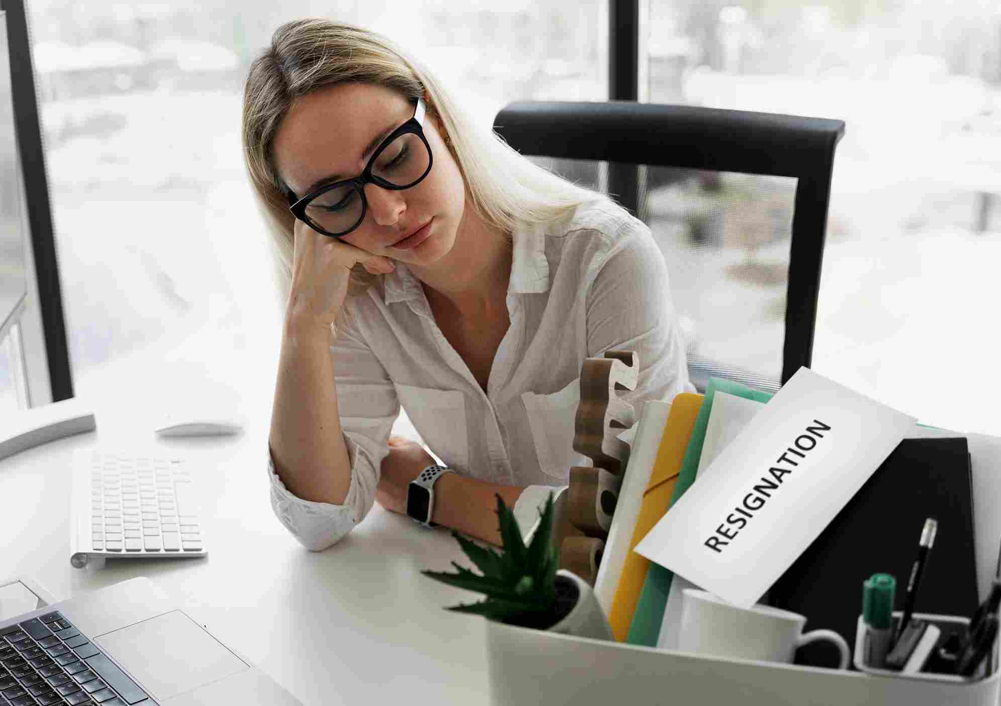 Employee resting head on desk near a resignation folder