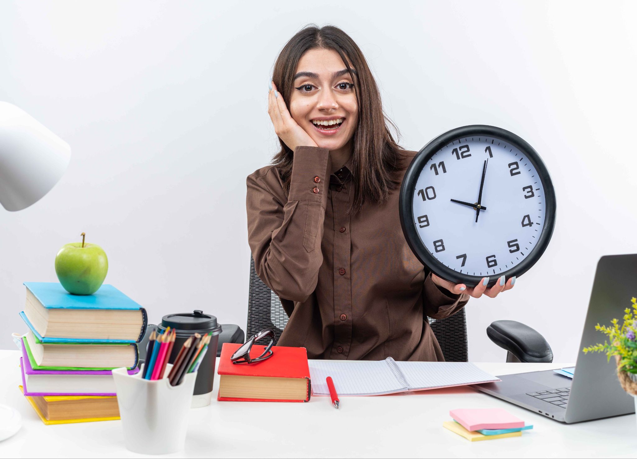 Woman sitting at desk holding a clock