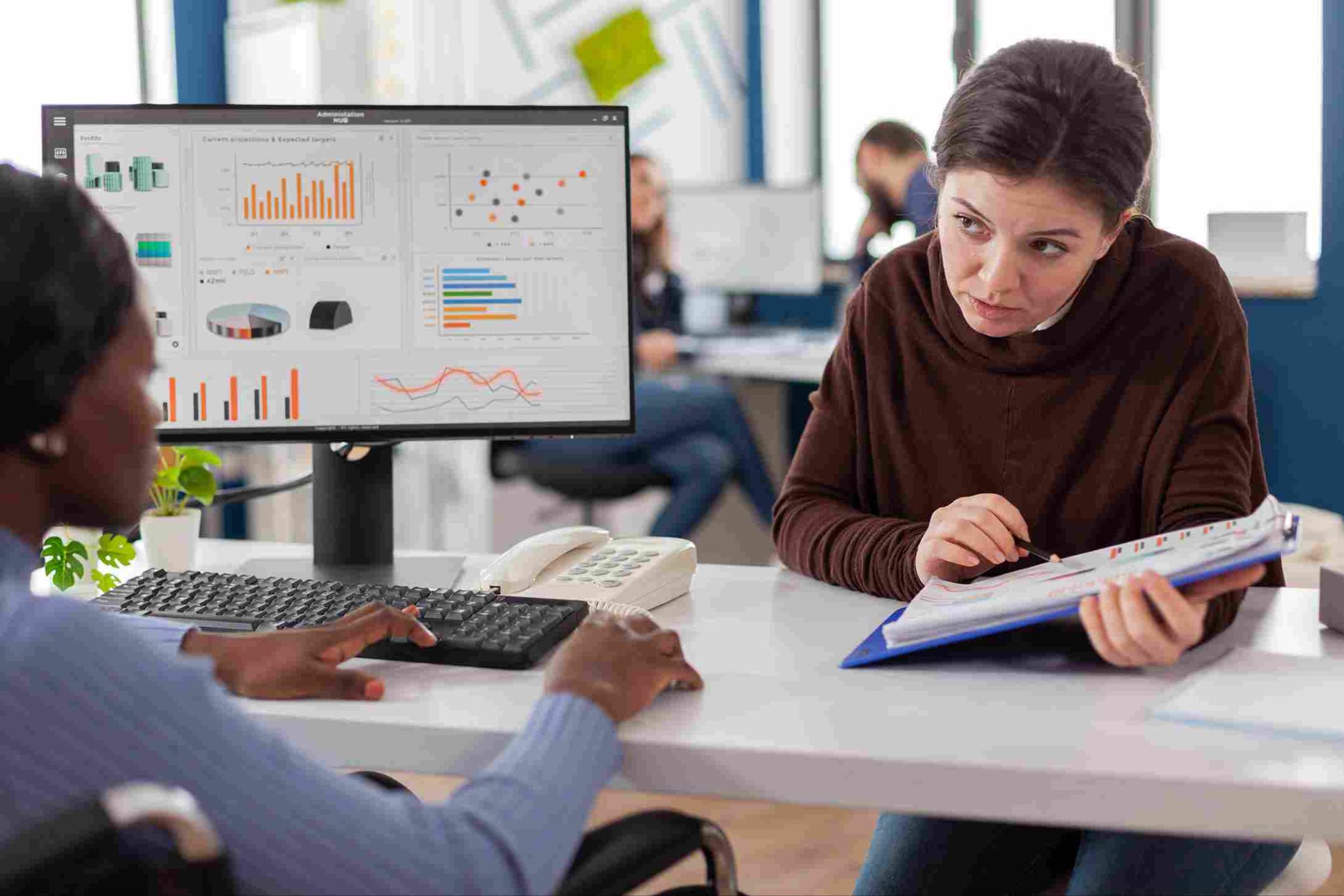 Two people discussing attendance report metrics on a computer