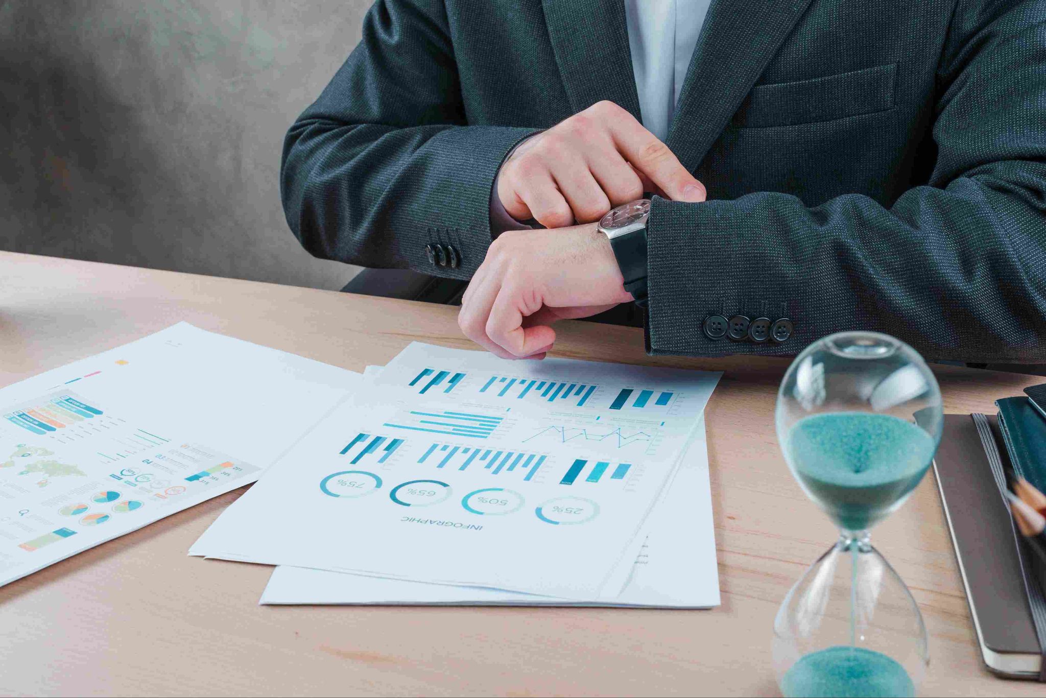Businessman looking at watch with charts on desk
