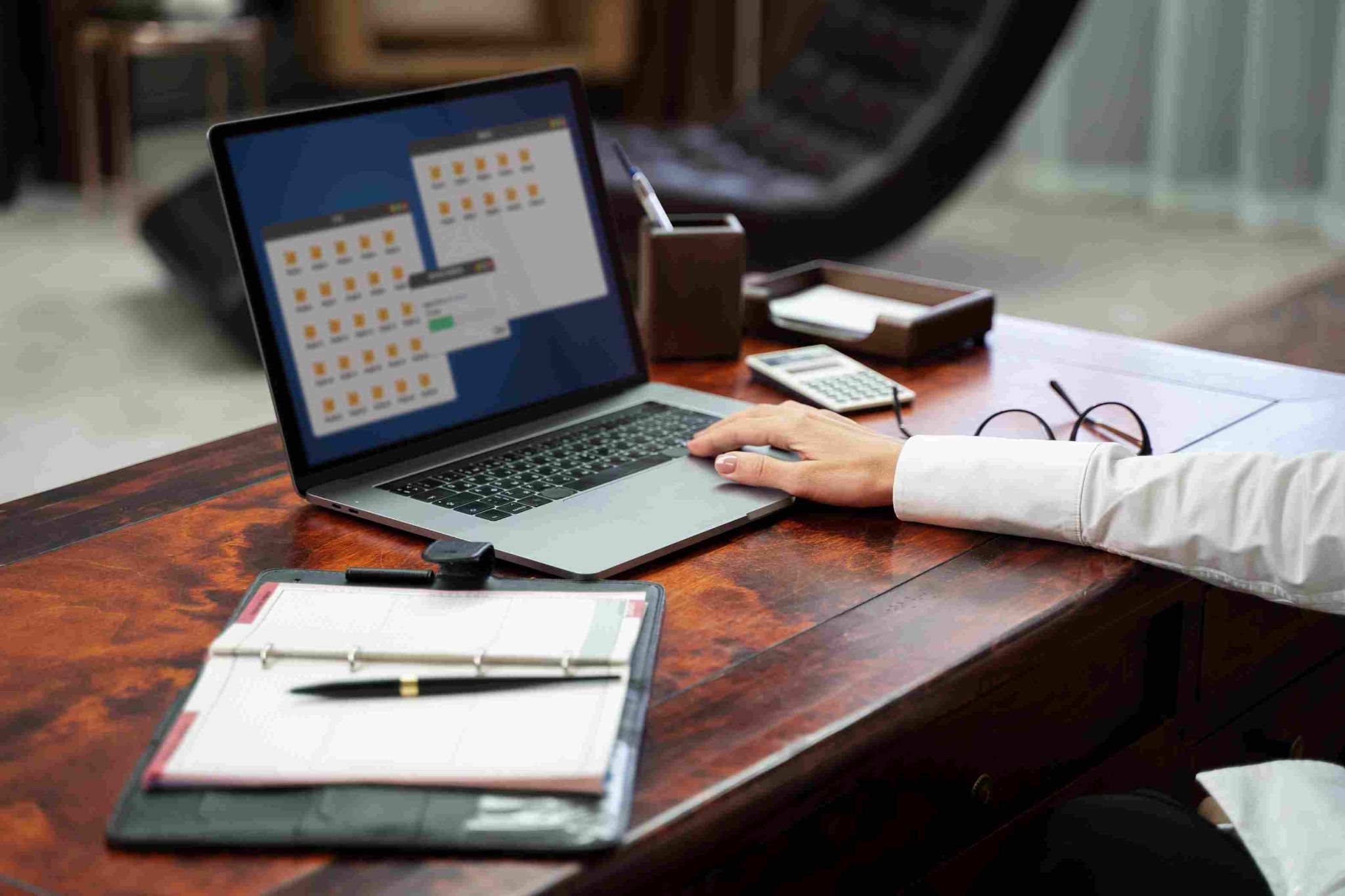 Person working on laptop with notebook