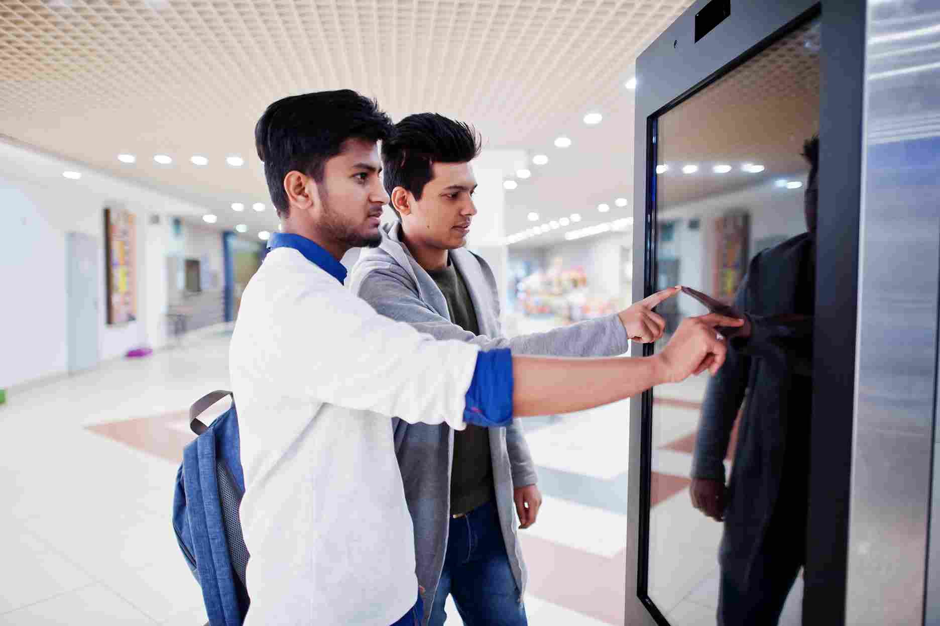 Two employees using a facial recognition time clock kiosk