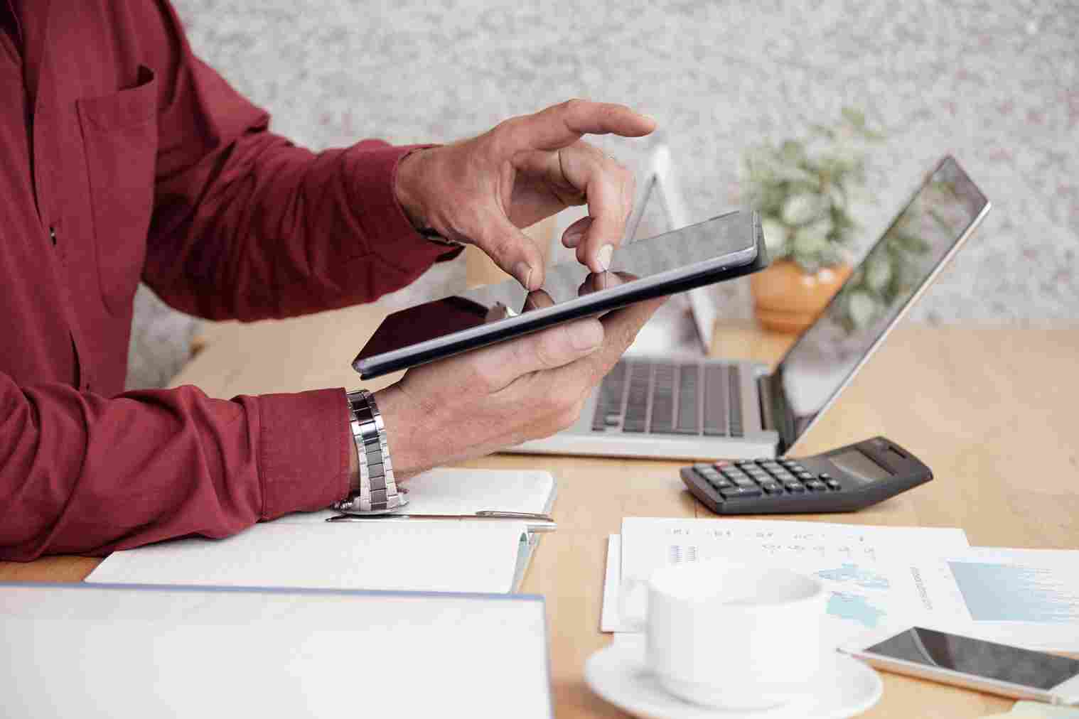 Person holding a tablet and calculator on a desk