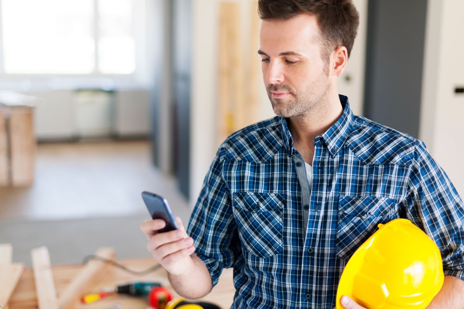 Construction worker holding a hard hat and smartphone