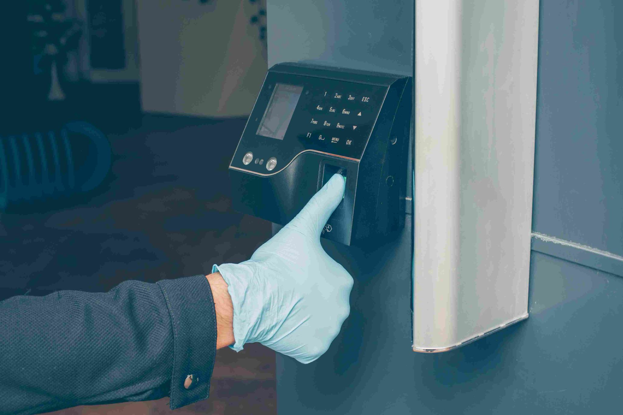Person wearing gloves using a fingerprint scanner and PIN pad